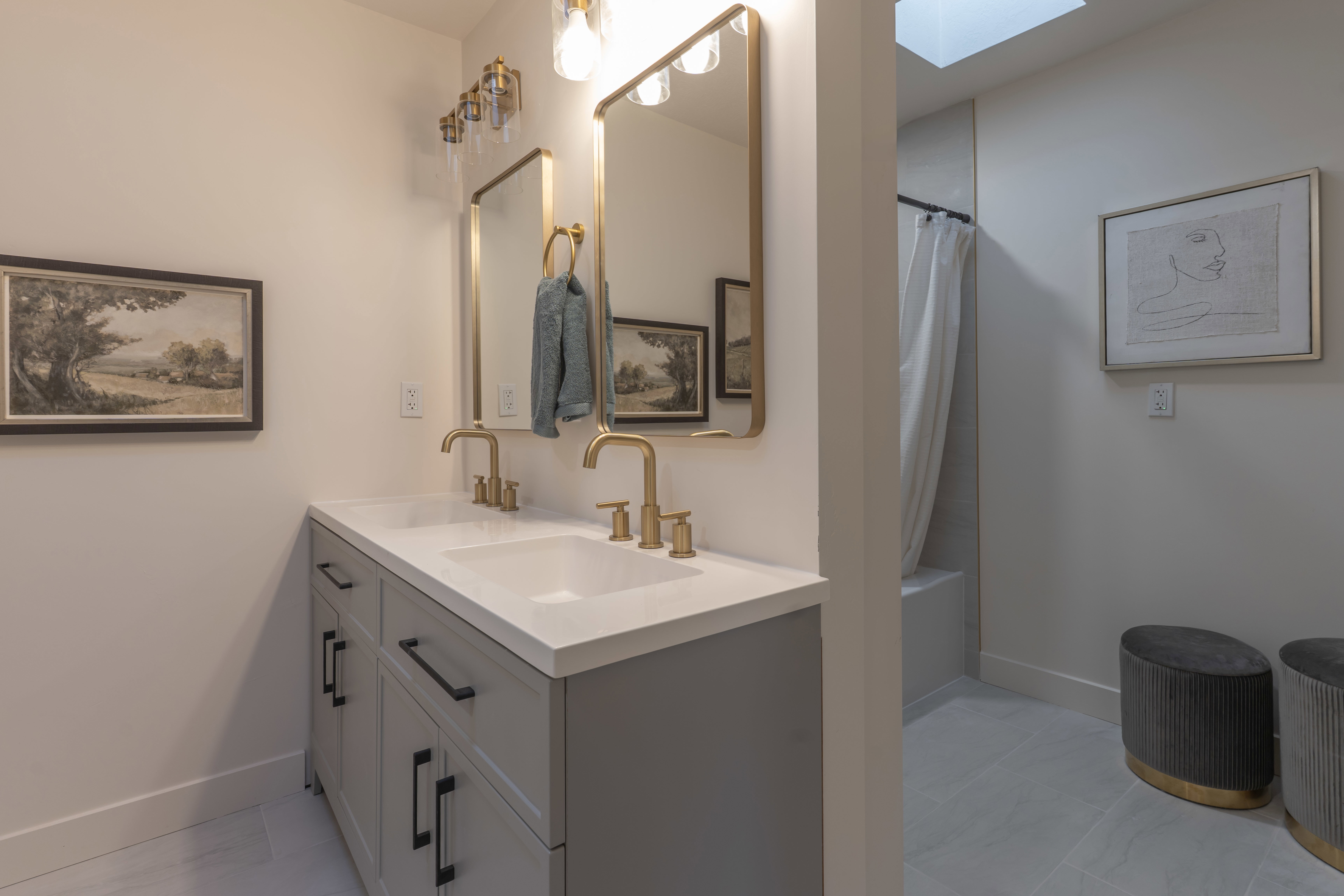 Bathroom with double vanity, shower / tub combo, and a skylight