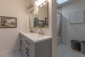 Bathroom with double vanity, shower / tub combo, and a skylight
