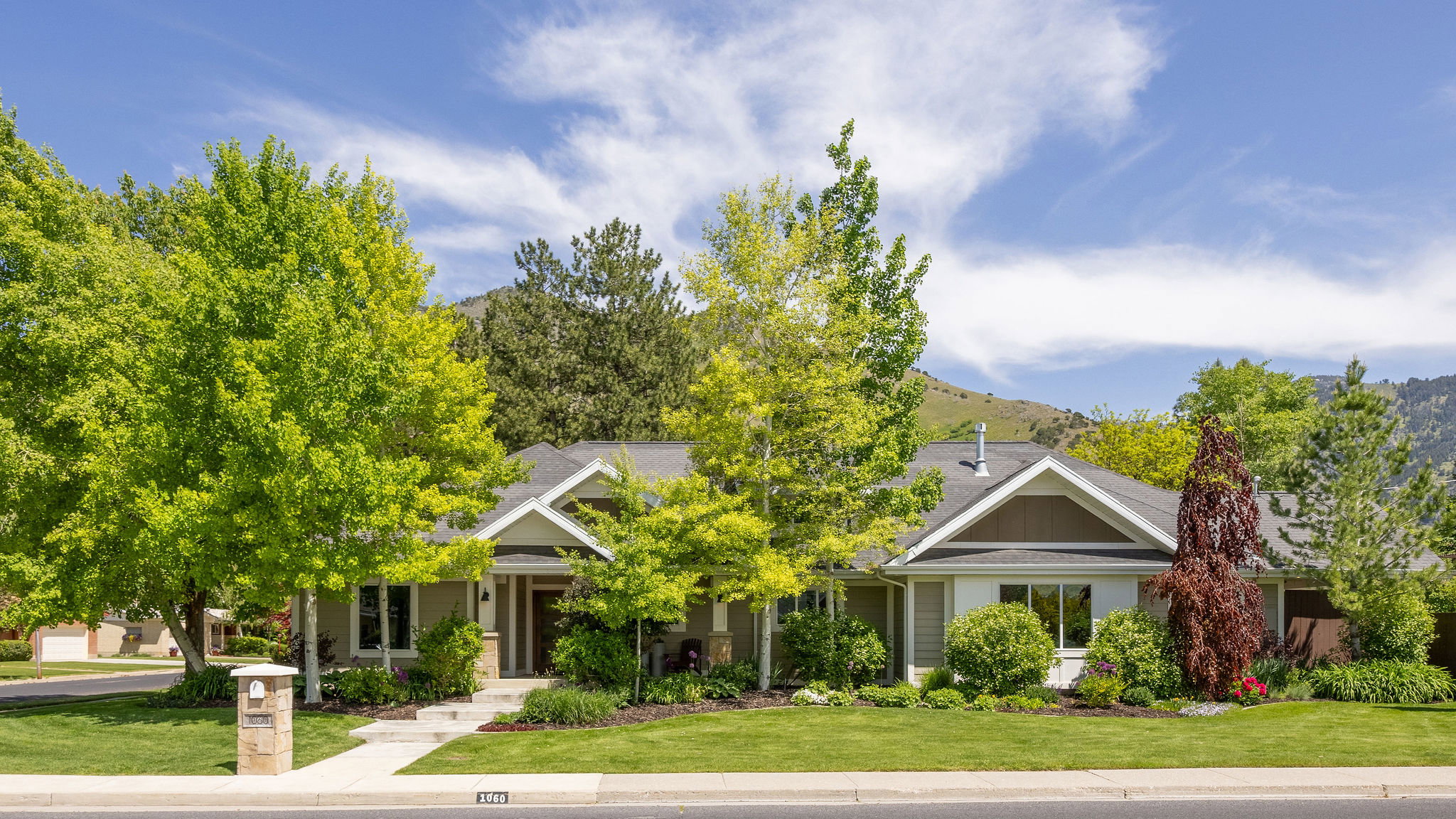 Front of home with full landscaping and mature trees