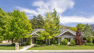 Front of home with full landscaping and mature trees