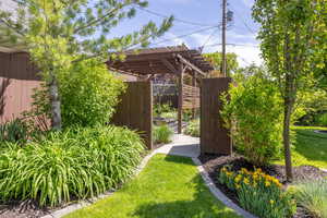 View of lawn and gate into backyard and pergola