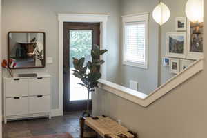 Mudroom off of garage with door to patio and laundry room and stairs to basement