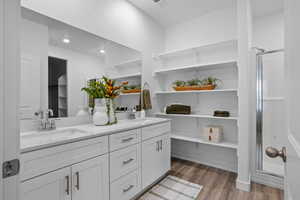 Bathroom with double vanity, light wood-style flooring, a stall shower, and recessed lighting