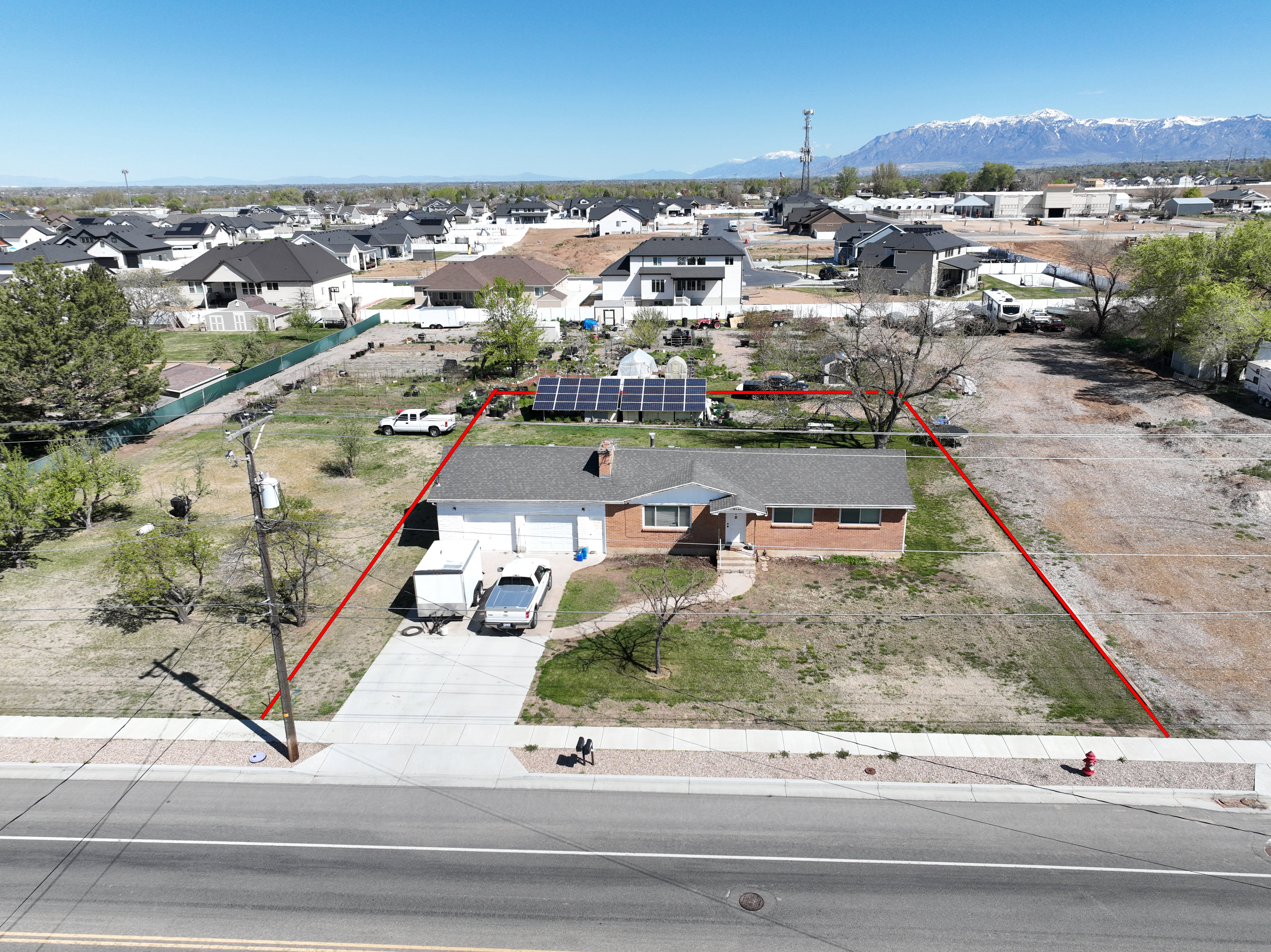 Aerial perspective of suburban area with property parcel outlined and a mountain backdrop