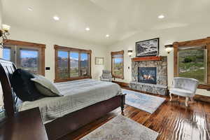Bedroom featuring vaulted ceiling, dark wood-style floors, a fireplace, access to exterior, and recessed lighting