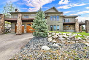 Rear view of property featuring stone siding, board and batten siding, and driveway