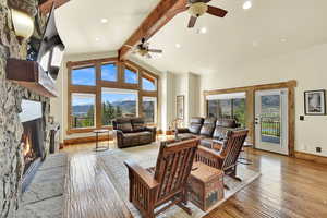 Living area with a stone fireplace, light wood finished floors, recessed lighting, and a ceiling fan
