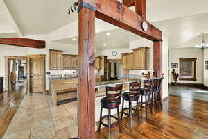 Kitchen featuring light stone counters, a breakfast bar area, a peninsula, wood finish cabinetry, and vaulted ceiling