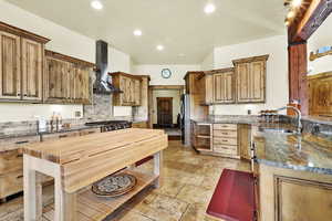 Kitchen featuring dark stone counters, stone tile flooring, a peninsula, stainless steel appliances, and recessed lighting