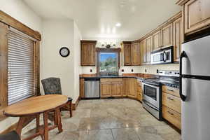 ADU Kitchen featuring stainless steel appliances, stone tile floors, and dark stone countertops