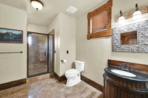 ADU Full bathroom with stone tile floors, vanity, and a shower stall