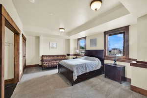 Carpeted bedroom featuring baseboards and a raised ceiling
