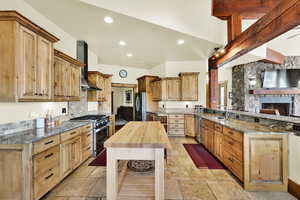 Kitchen featuring dark stone countertops, a peninsula, stainless steel appliances, a fireplace, and stone tile floors