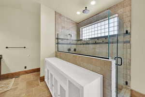 Full bathroom featuring stone tile floors, a stall shower, and recessed lighting