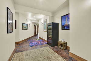 Hall featuring baseboards and dark stone finish floors