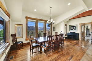 Dining area featuring a mountain view, wood-type flooring, hanging lights, and beam ceiling