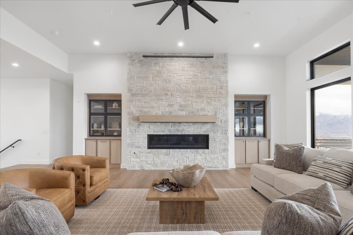 Living area with wood finished floors, a stone fireplace, a ceiling fan, and recessed lighting