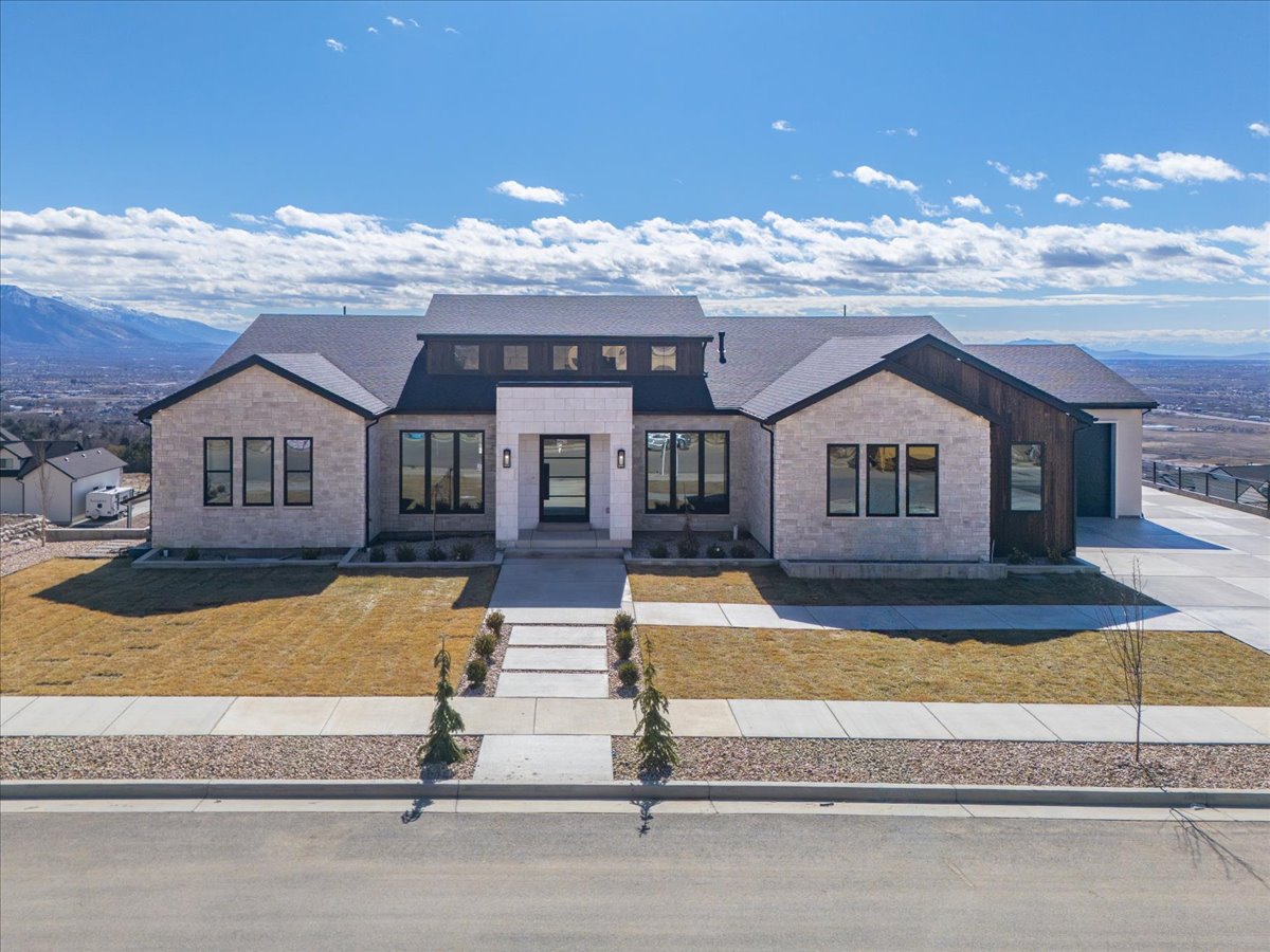 View of front facade featuring a shingled roof, a mountain view, and a front lawn