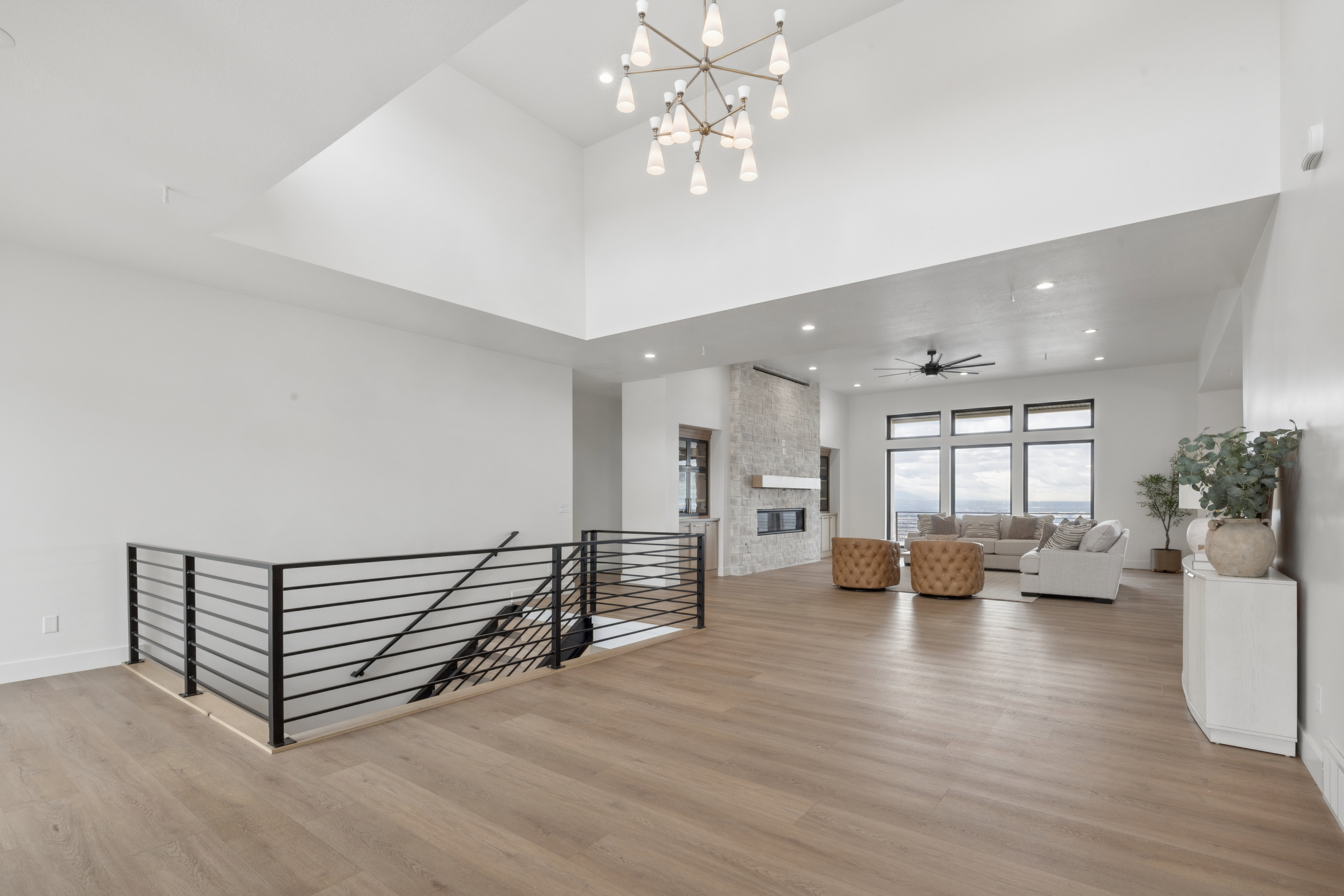 Stairs with a high ceiling, a chandelier, wood finished floors, a fireplace, and ceiling fan