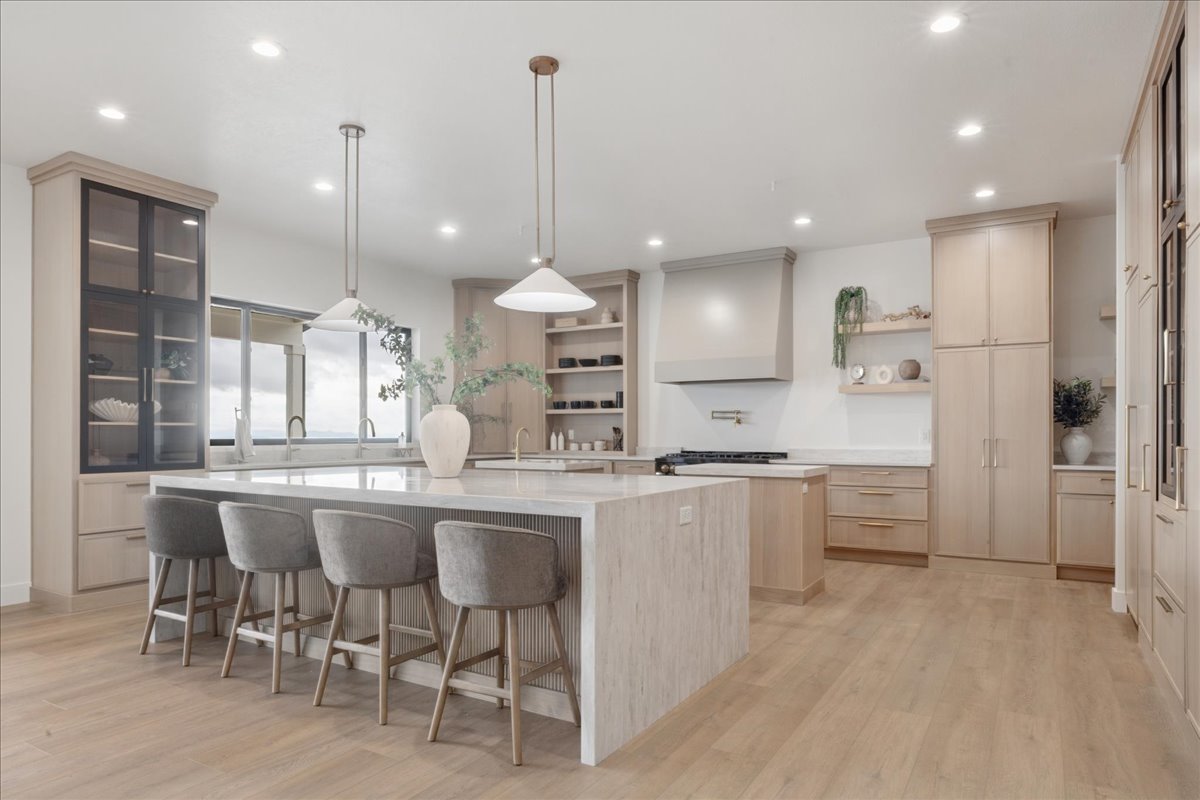 Kitchen with a large island with sink, light stone countertops, open shelves, pendant lighting, and light wood finish cabinets