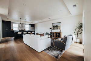 Living room featuring recessed lighting, dark wood finished floors, and a tray ceiling
