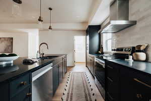 Kitchen featuring stainless steel appliances, dark stone counters, pendant lighting, and dark cabinets
