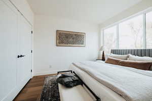 Bedroom with dark wood-style flooring and a closet