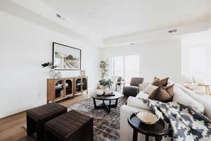 Living area with wood finished floors and a raised ceiling