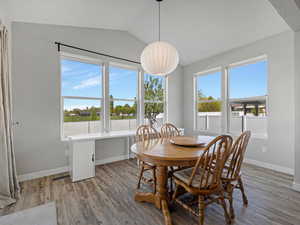 Dining room with light wood-style flooring, vaulted ceiling, and plenty of natural light