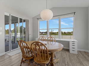 Dining room with lofted ceiling, light wood-type flooring, and plenty of natural light