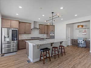 Kitchen with stainless steel appliances, a kitchen breakfast bar, light stone counters, pendant lighting, and an office area