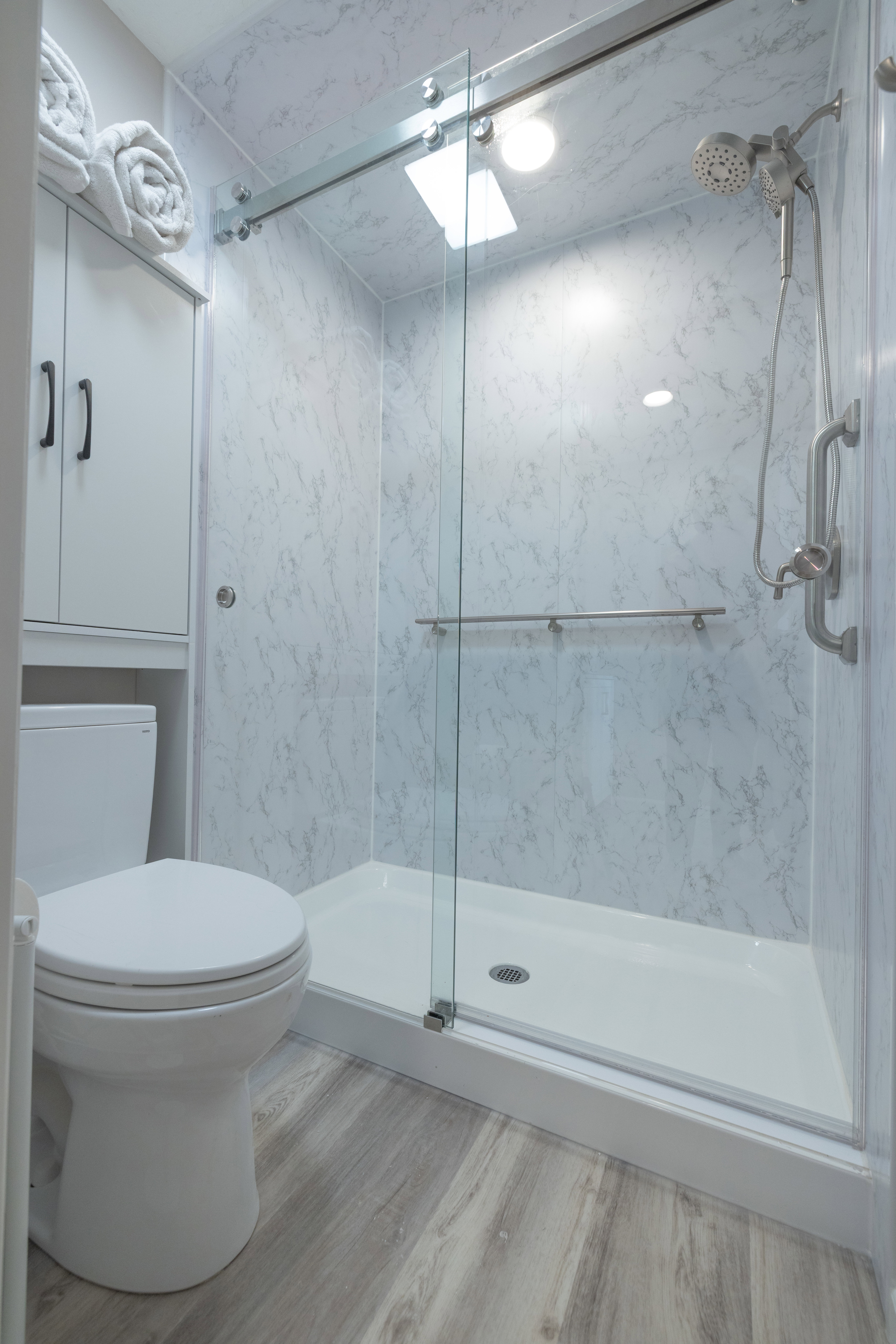 Shower with clear glass sliding door, dual shower heads, and an integrated grab bar