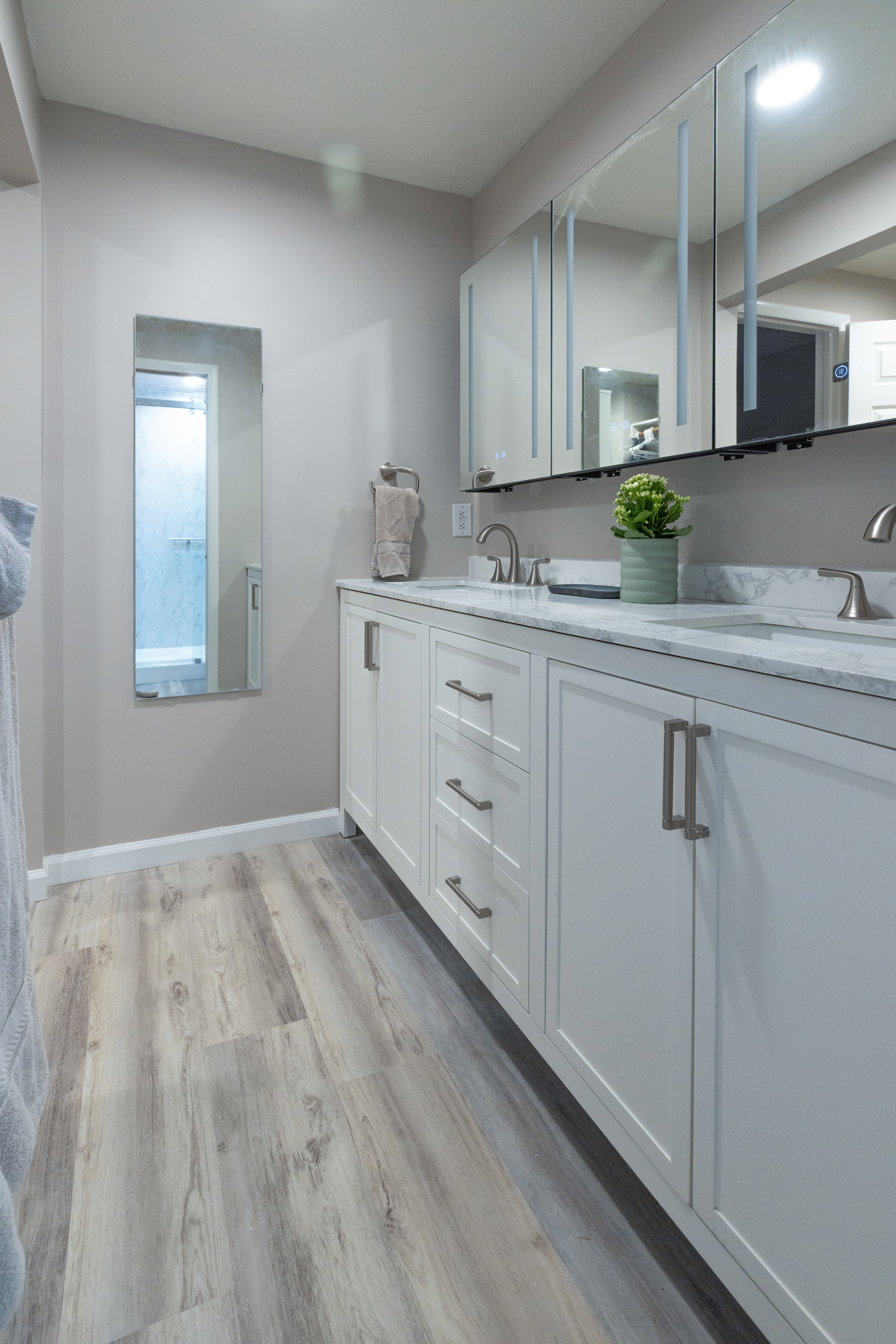 Bathroom vanity with dual undermount sinks, stone-finish countertop, and white shaker-style cabinetry