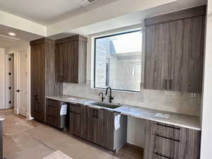 Kitchen with tasteful backsplash, modern cabinets, and light stone countertops