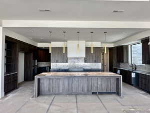 Kitchen with dark wood finish cabinetry, light stone counters, modern cabinets, and pendant lighting