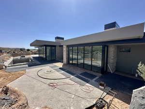 Back of property with a chimney, stone siding, a patio area, and stucco siding