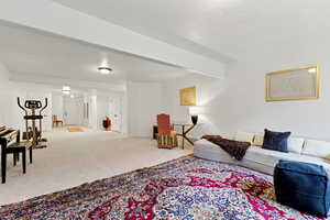 Living room with light carpet, beam ceiling, and a textured ceiling