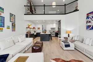 Living room with light wood-style flooring, recessed lighting, and a high ceiling