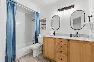 Full bathroom with double vanity, shower / bathtub combination with curtain, and light tile patterned floors