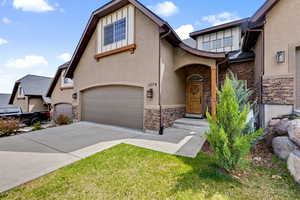 View of front of home featuring stone siding, stucco siding, driveway, and a garage