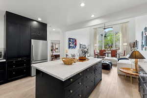 Kitchen featuring dark cabinets, open floor plan, light stone counters, and recessed lighting