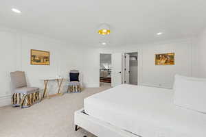 Bedroom with a decorative wall, recessed lighting, a walk in closet, and light carpet