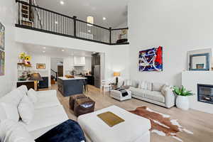 Living room featuring a glass covered fireplace, light wood-style flooring, recessed lighting, and a high ceiling