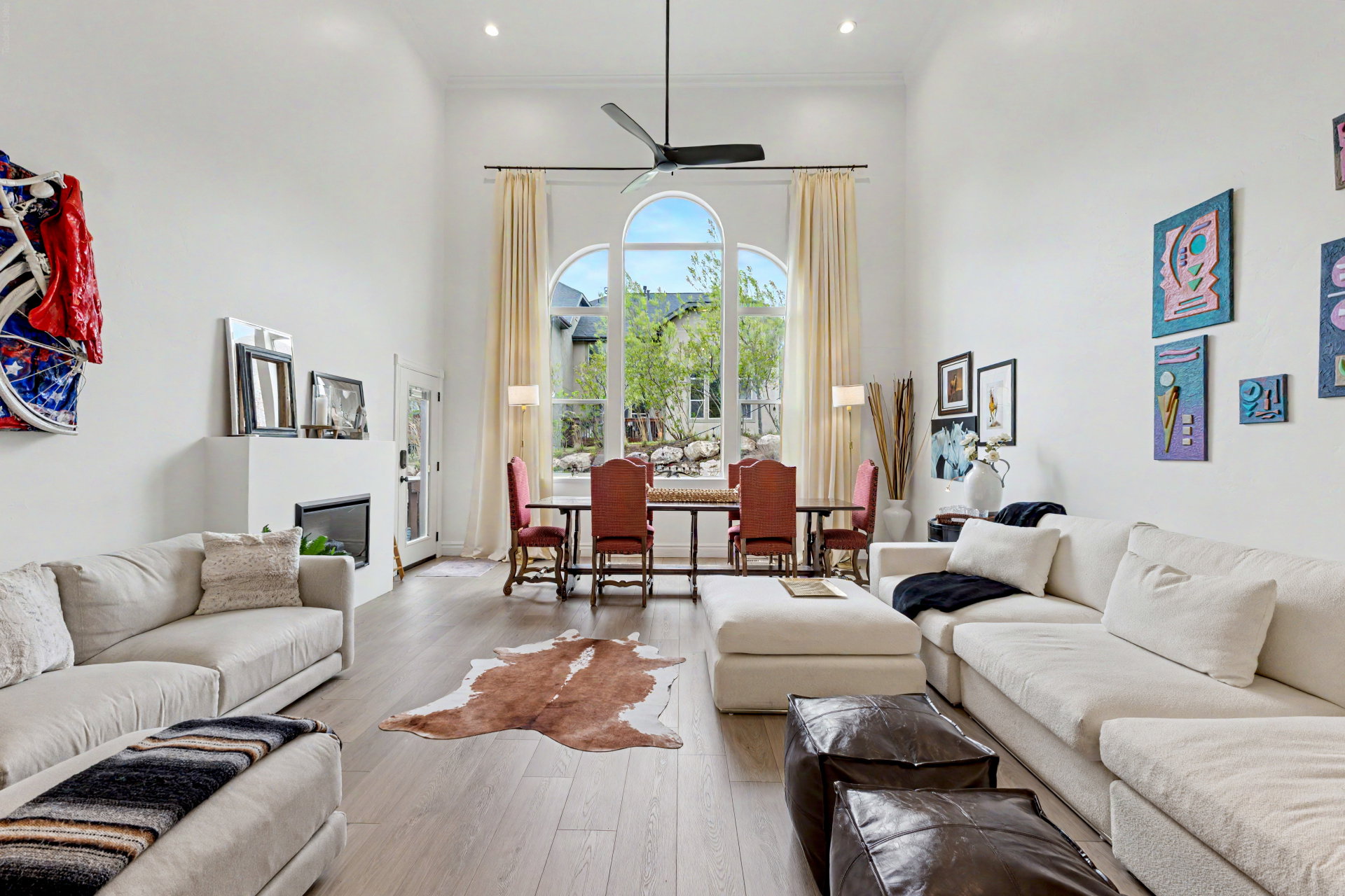 Living area featuring a high ceiling, hardwood / wood-style flooring, ceiling fan, a glass covered fireplace, and recessed lighting