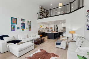 Living room with light wood-style flooring, recessed lighting, and a high ceiling