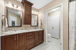 Bathroom with double vanity, a shower with shower curtain, and light tile patterned flooring