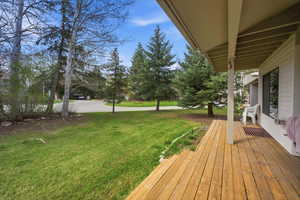 View of grassy yard featuring a wooden deck