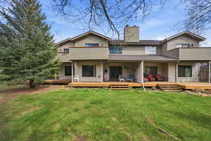 Back of property with a yard, a chimney, a shingled roof, and covered porch