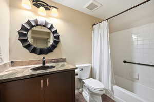 Bathroom with vanity, shower / bath combo, and a textured wall
