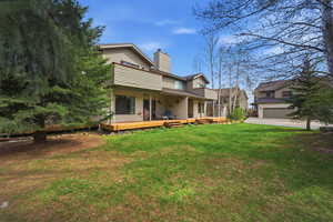 Rear view of property featuring a chimney and a yard